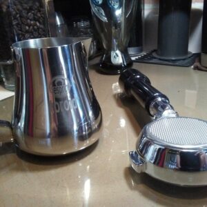 Bottomless portafilter and milk pitcher on a kitchen countertop