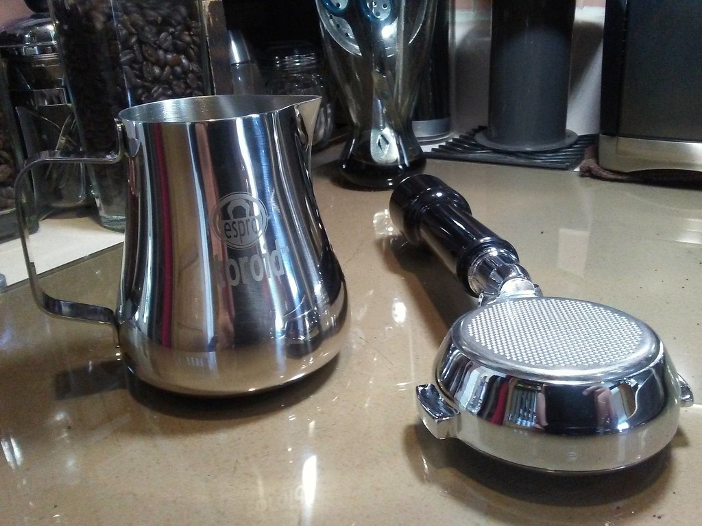 Bottomless portafilter and milk pitcher on a kitchen countertop