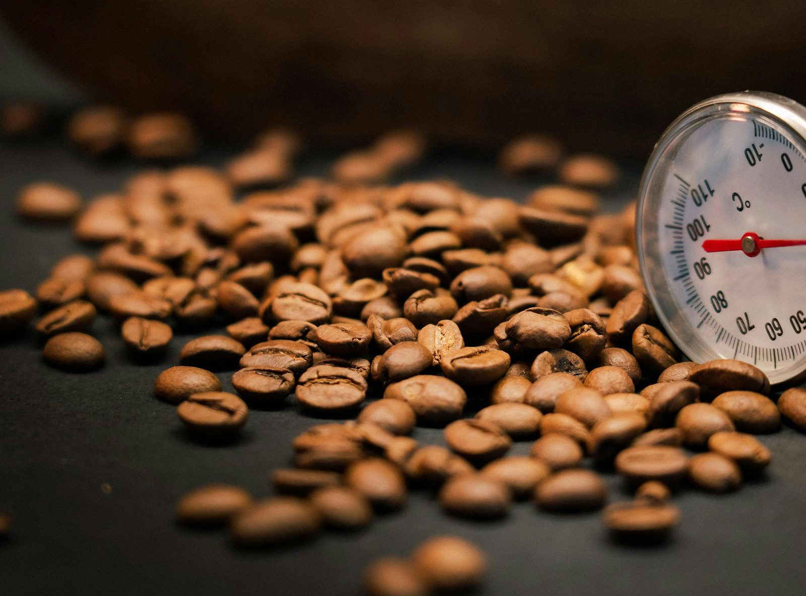 Coffee beans with a thermometer, used to explain temperature stability in espresso brewing
