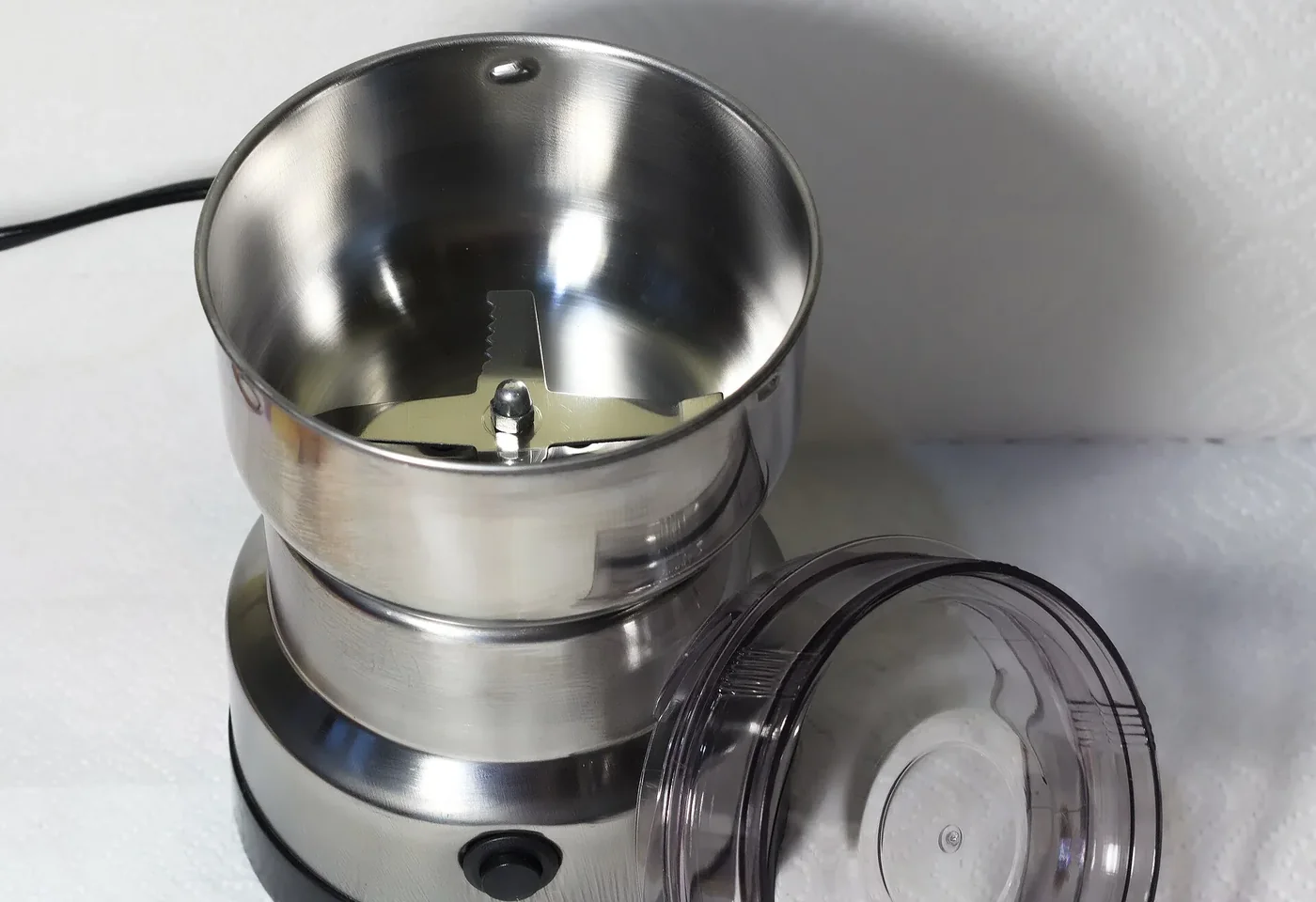 Open electric blade coffee grinder with its spinning metal blade visible