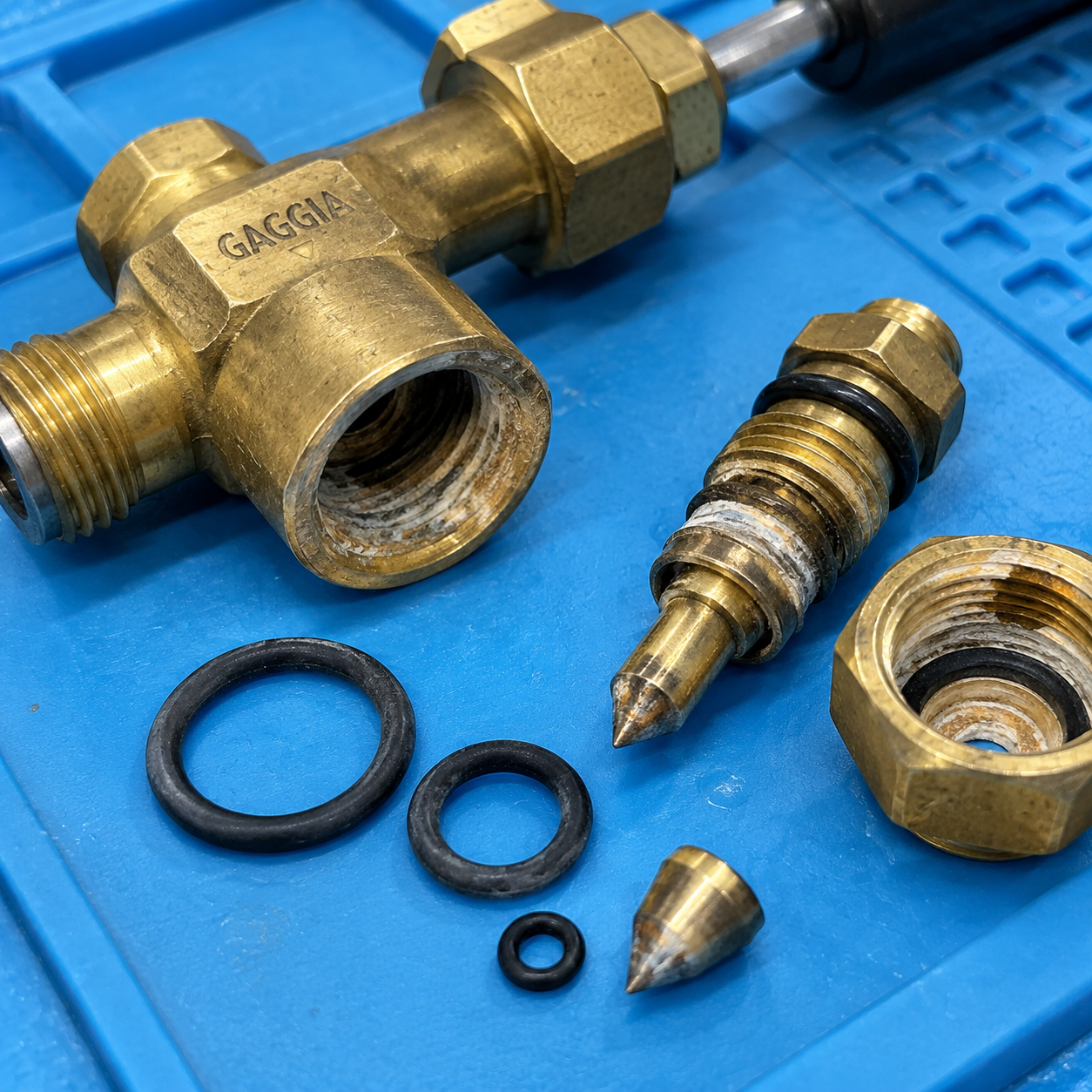 Disassembled brass steam valve components showing internal needle cone and sealing surfaces