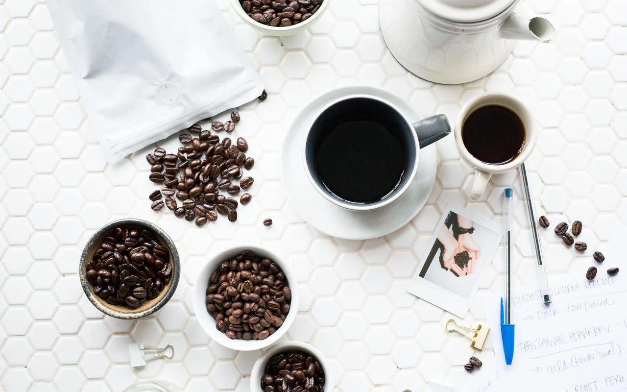 Brewed coffee and several portions of roasted beans on a tasting table