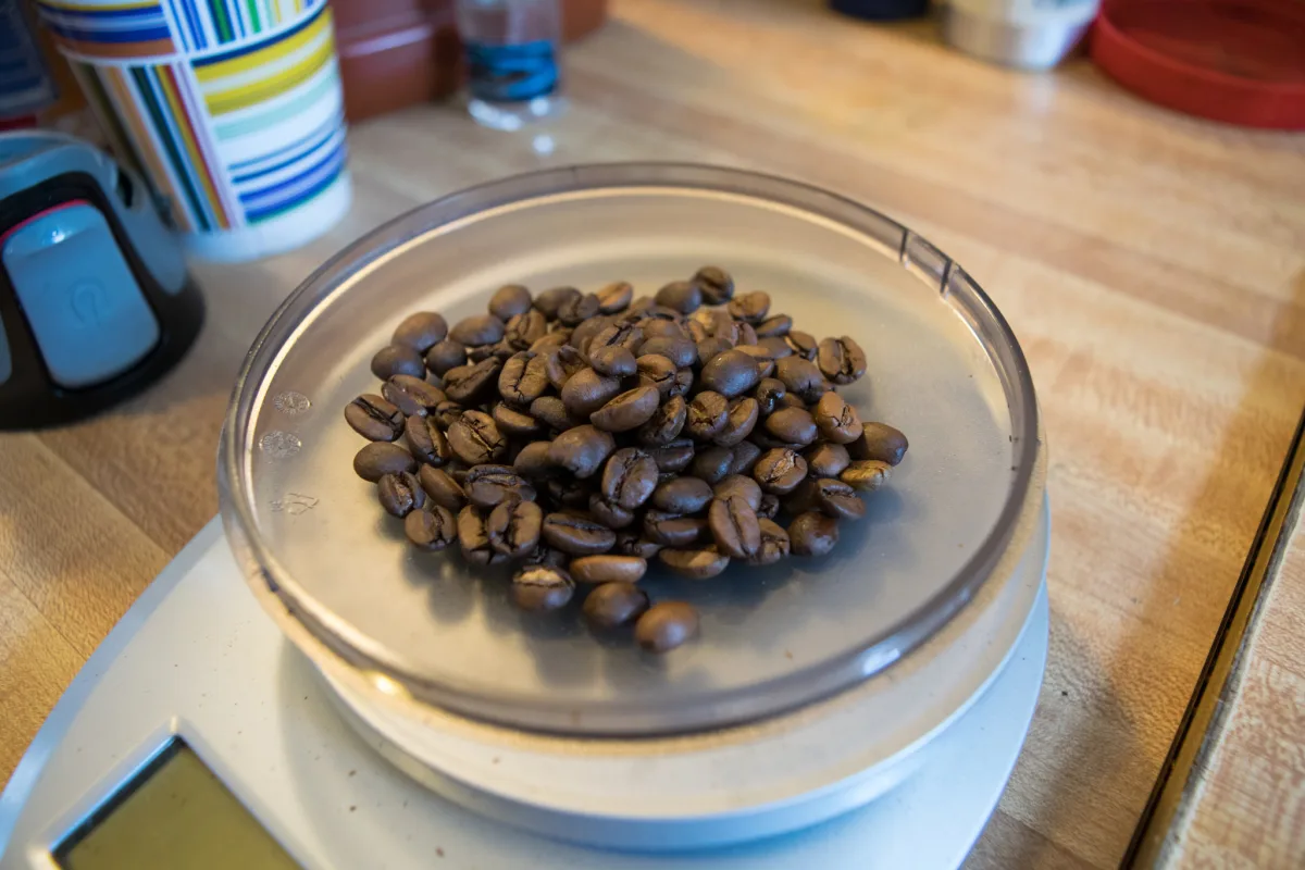 Whole roasted coffee beans on a kitchen scale