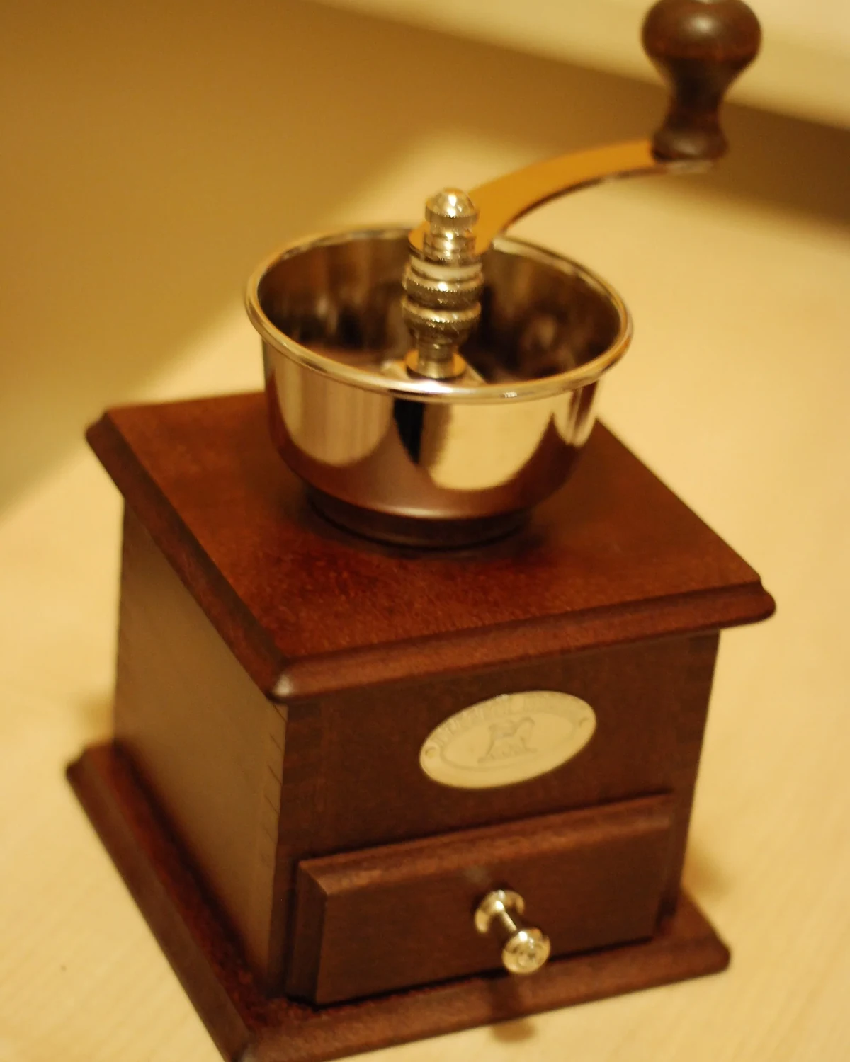 Wooden hand crank coffee grinder with a metal hopper and grounds drawer