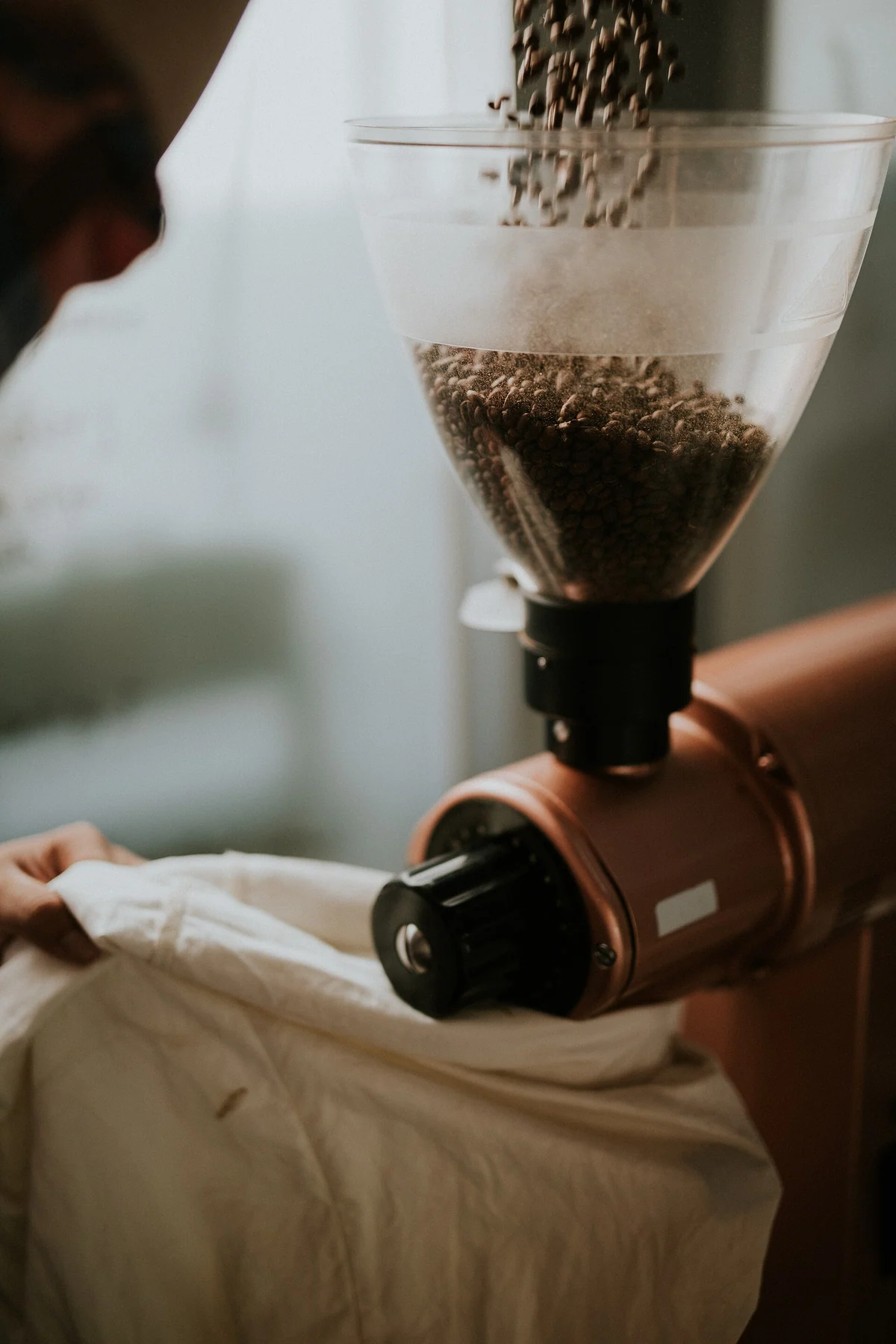 Roasted coffee beans falling into the hopper of a grinder