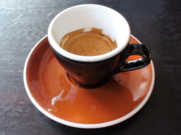Espresso in a black cup on a terracotta-colored saucer