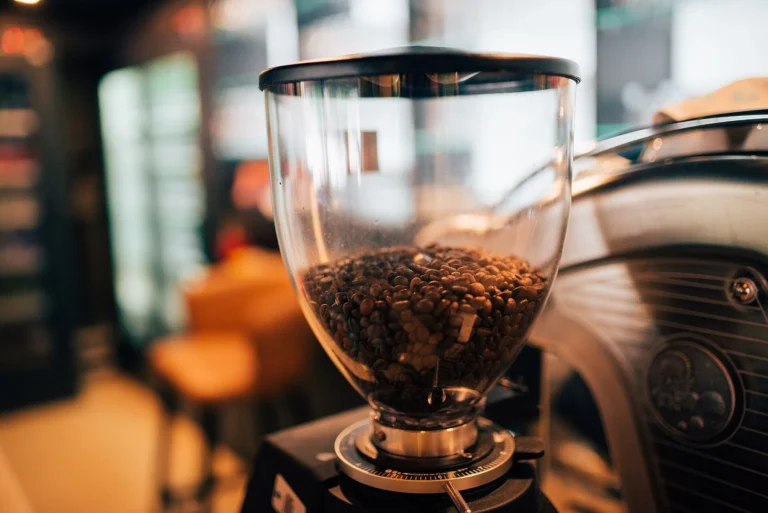 An electric coffee grinder with beans in its hopper on a café counter