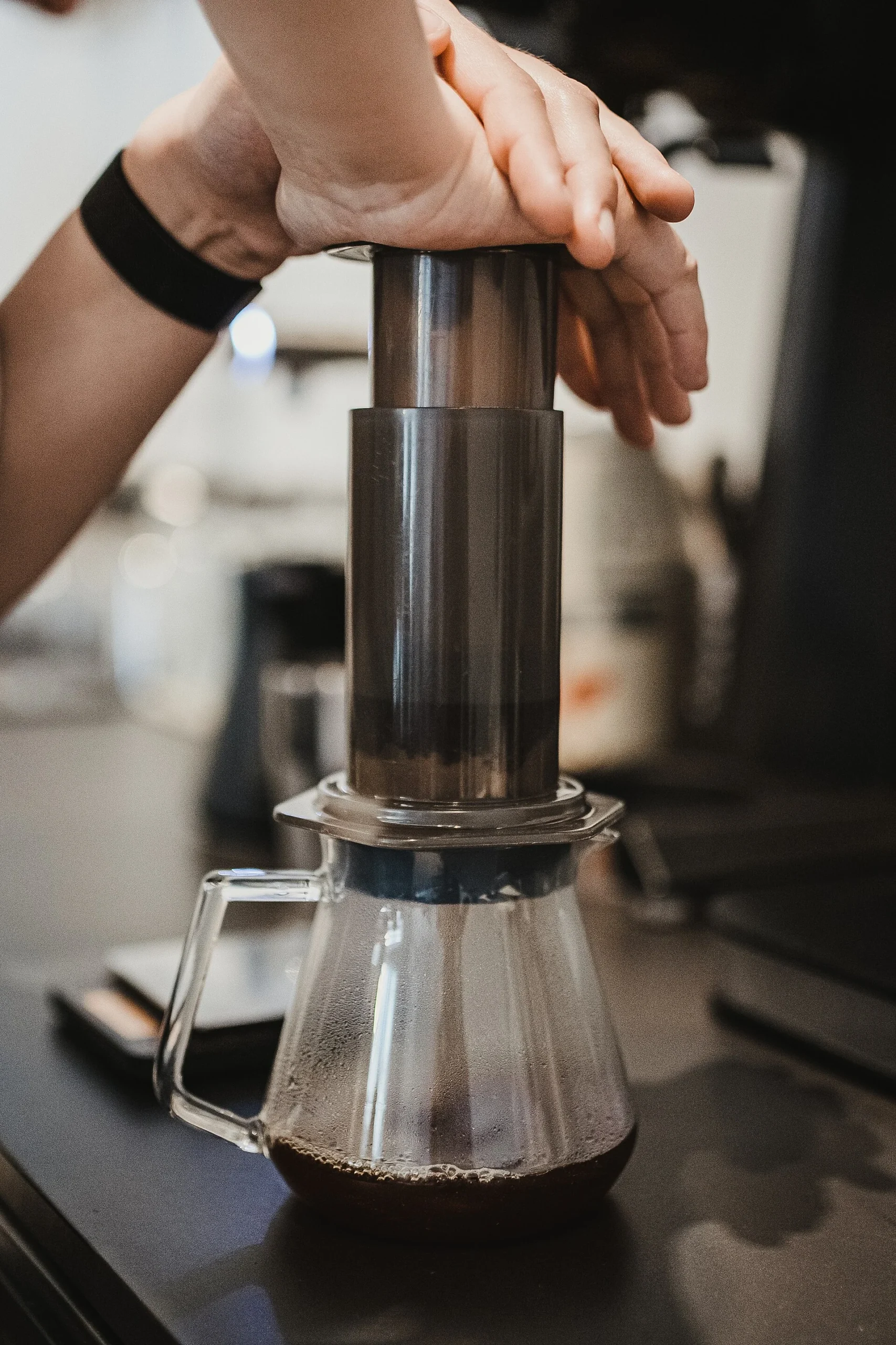 Hands pressing an AeroPress into a glass server