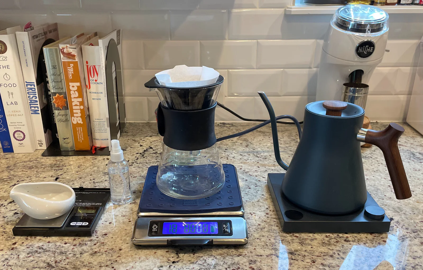 An empty paper filter seated in a V60 beside a kettle and grinder before coffee is added